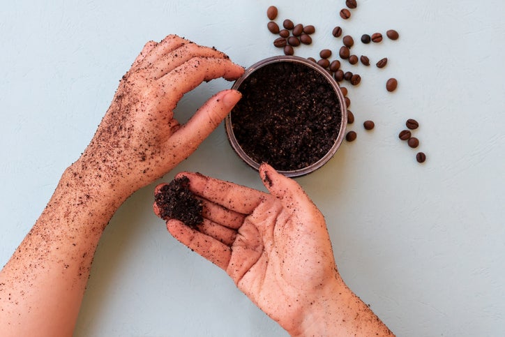 Top view of woman hands and jar with roasted coffee bean scrub and sea salt on mint background. National Coffee Day