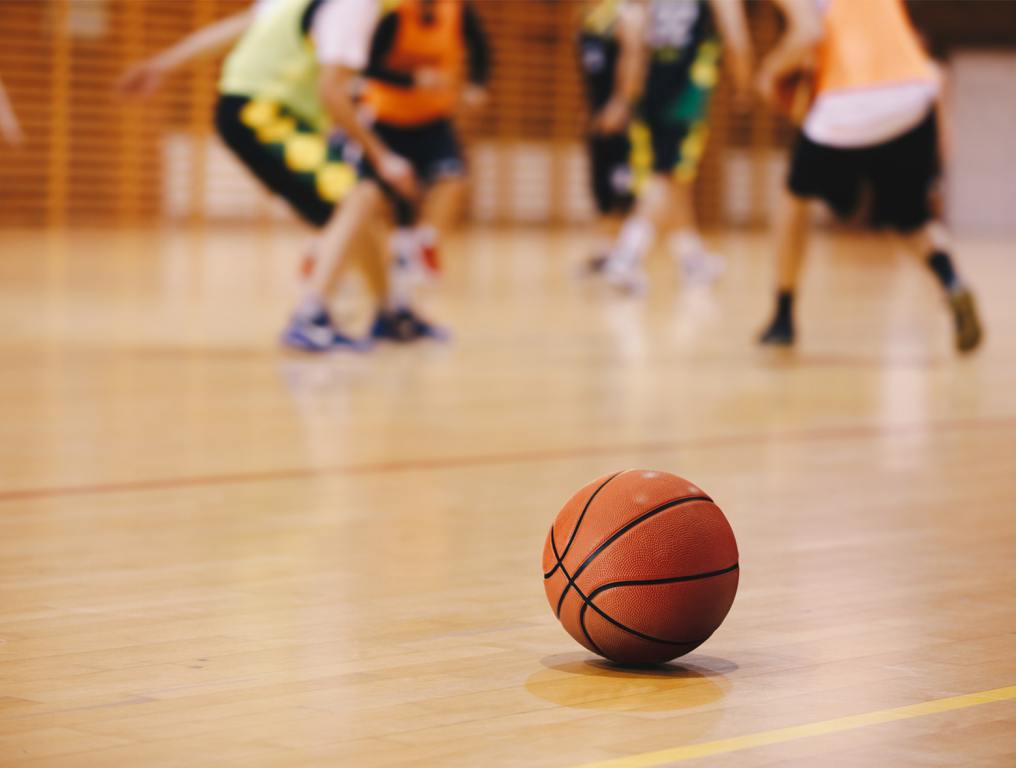 Basketball sitting on court floor wiht players feet in the background - Augusta university Sports Department